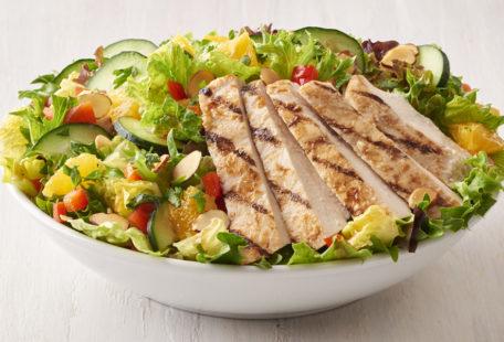 Asian Chicken Salad with oranges, cucumbers, red bell pepper, almonds in a bowl