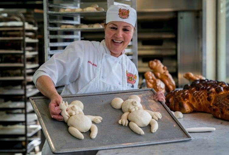 Baker smiling and showing critter breads on a baking pan